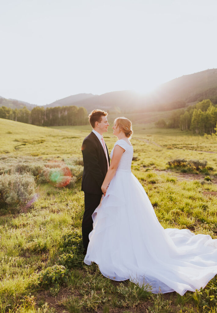 Wedding couple holds hands in beautiful field