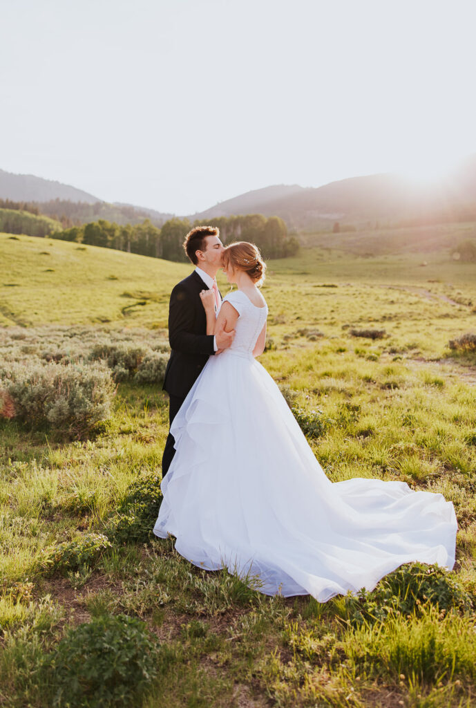Groom kisses bride in beautiful wedding pose