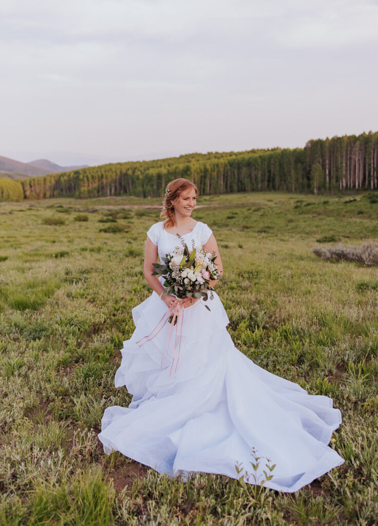 Bride poses in green Utah field at sunset