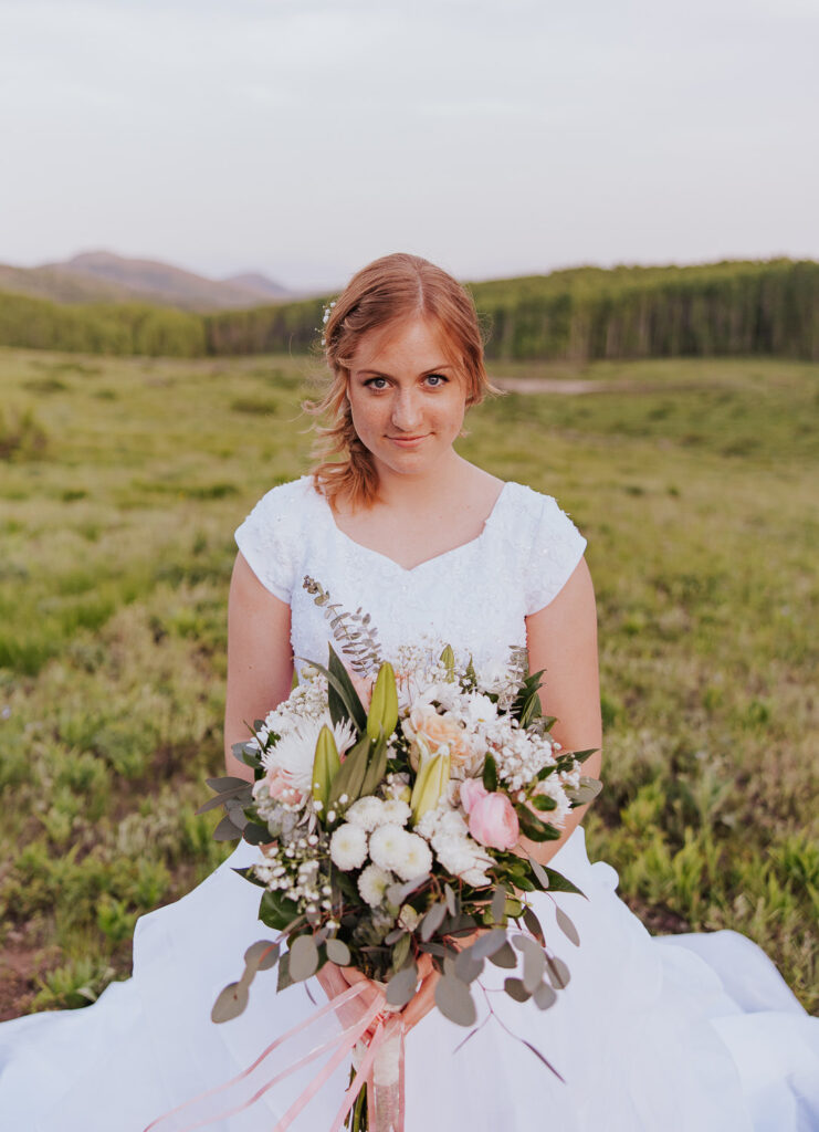 Bride poses with white wedding bouquet