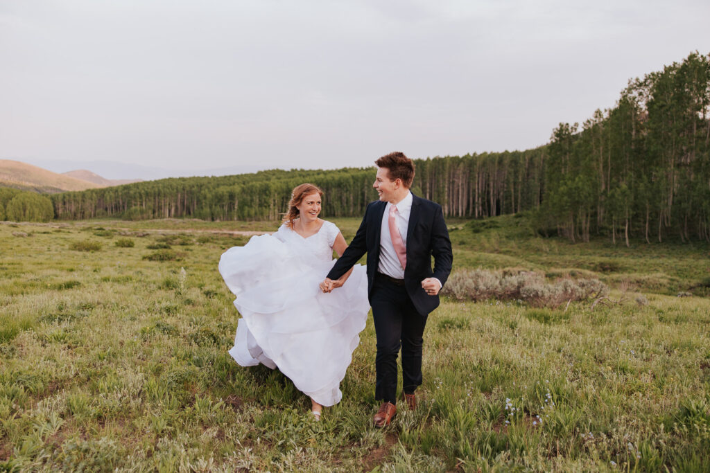 Bride and groom run through field in Utah wedding
