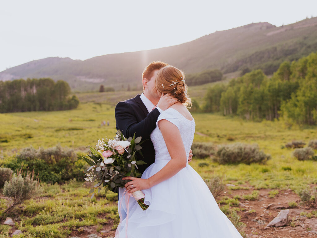 Sun flare as bride and groom kiss before Utah wedding