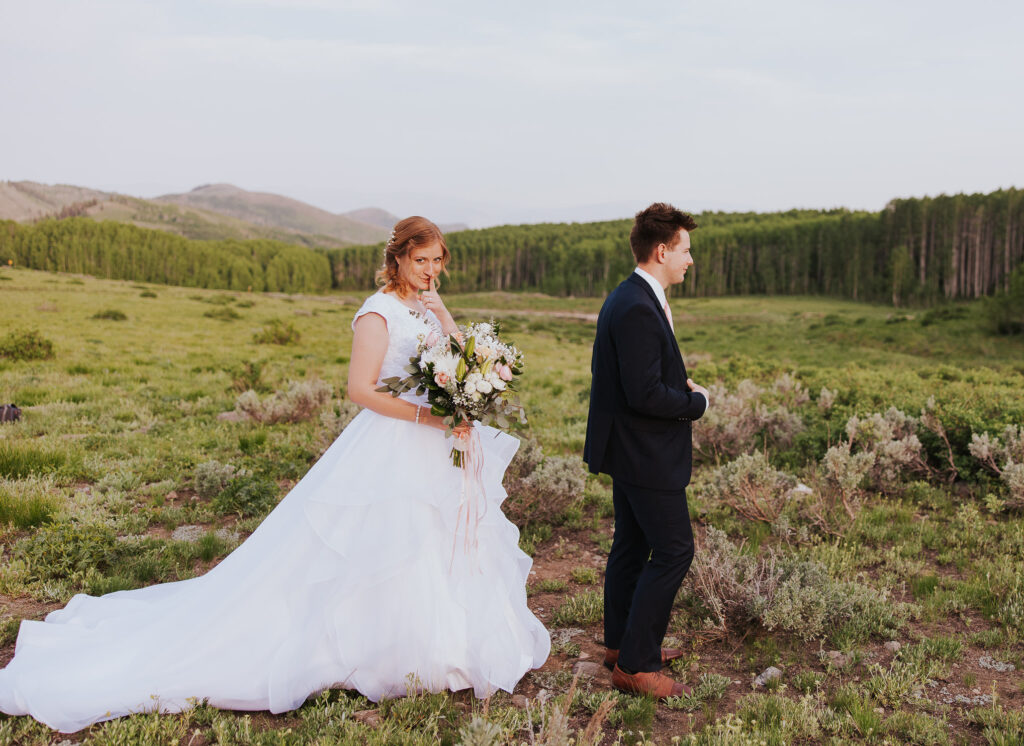 Bride stands behind groom before first look at Utah wedding