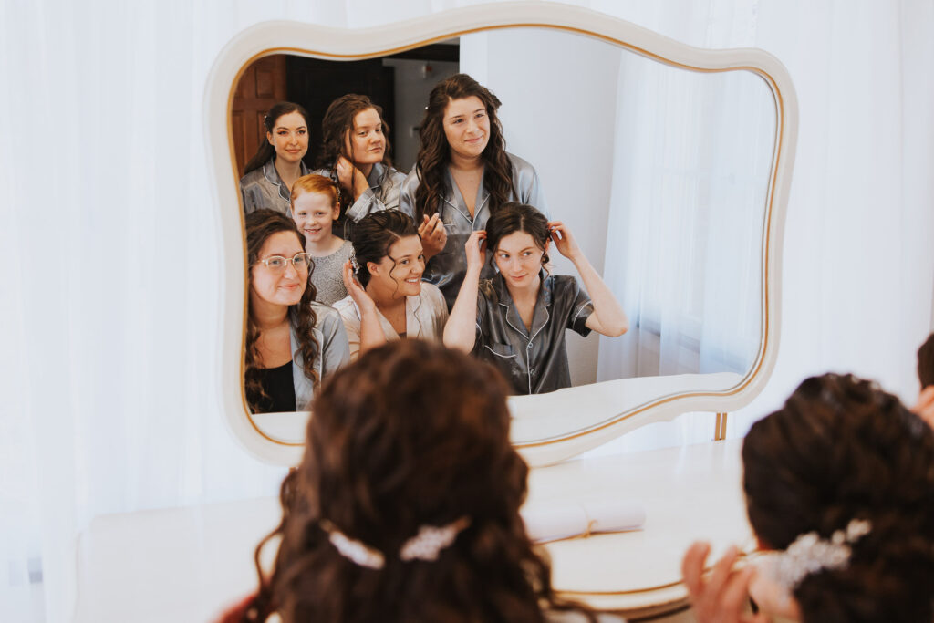 Bridesmaids do their hair and makeup in mirror
