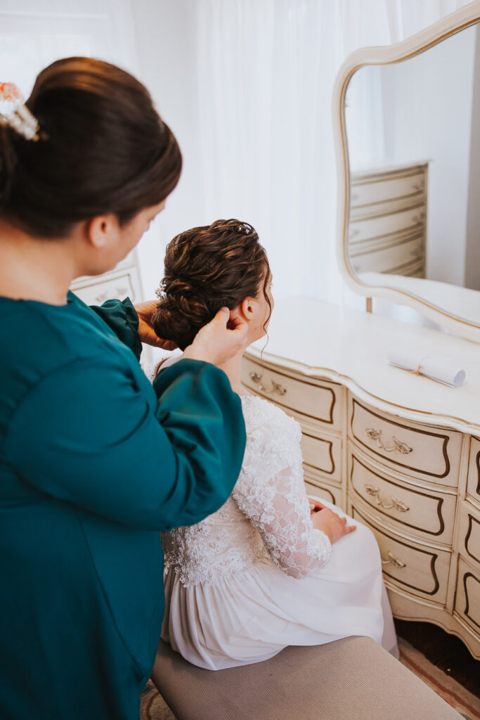 Mother helps bride with her wedding day hair