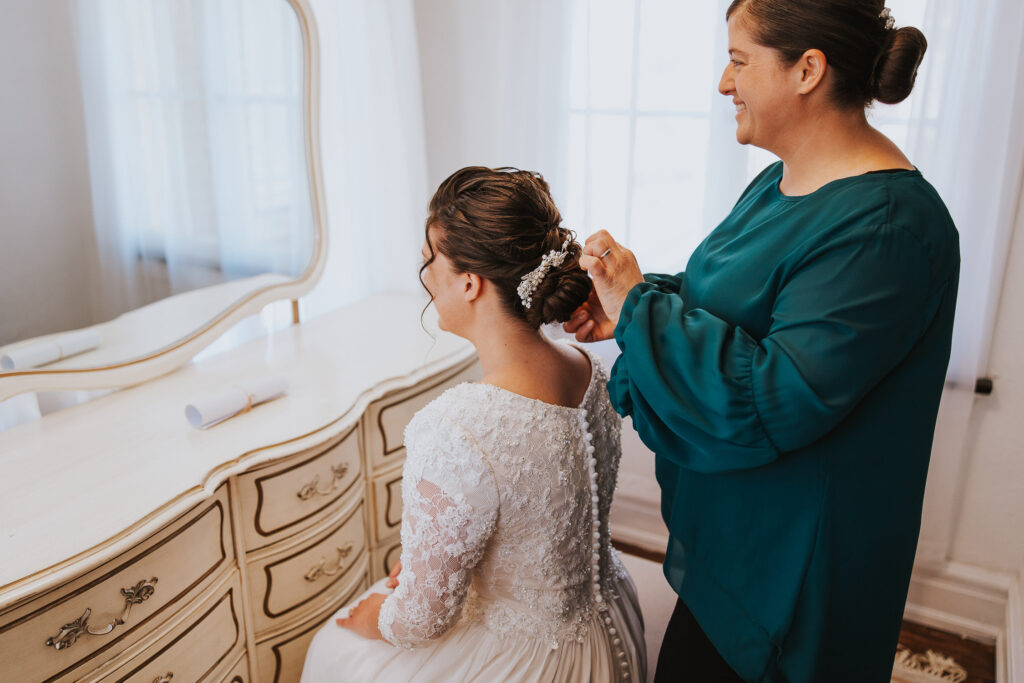 Mother puts broach in bride's hair before wedding ceremony in Toledo, Ohio