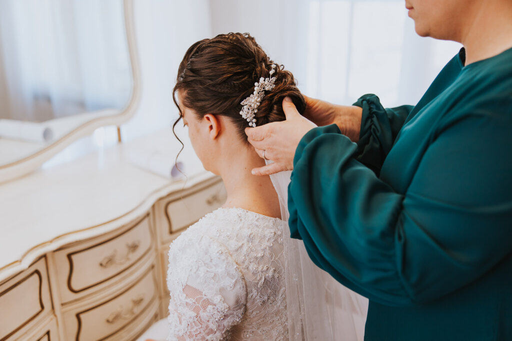 Mother secures hairpiece in bridal updo in Toledo, Ohio