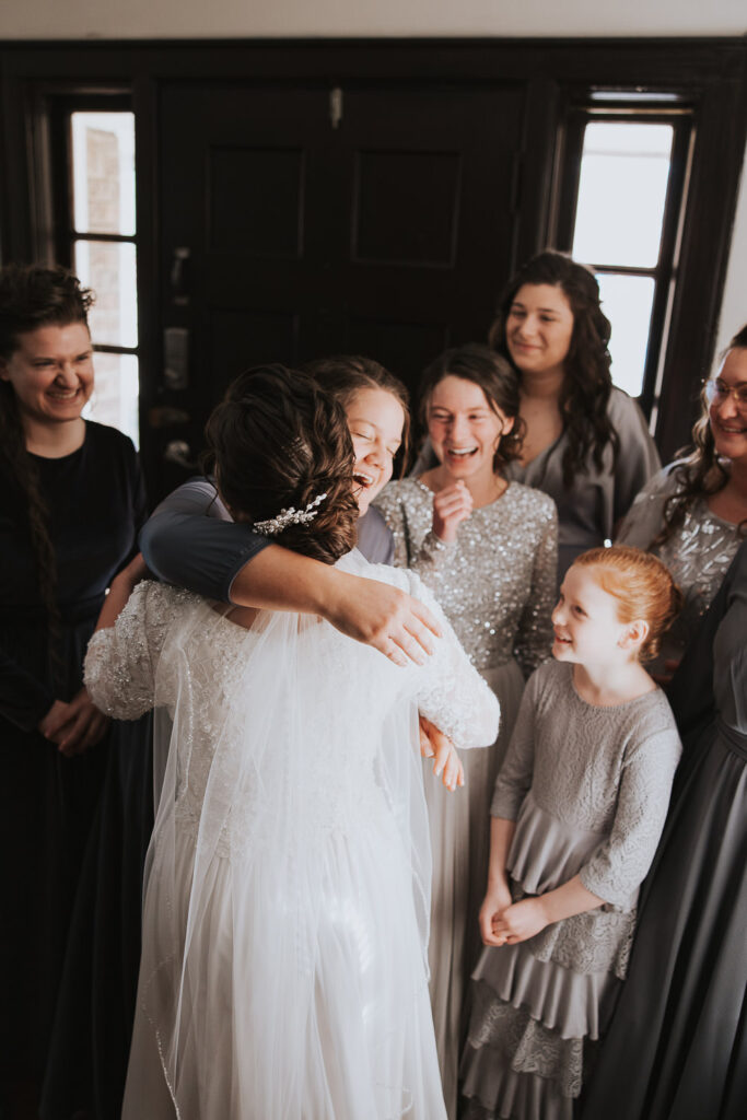 Sisters of the bride react to seeing her white wedding dress with long veil