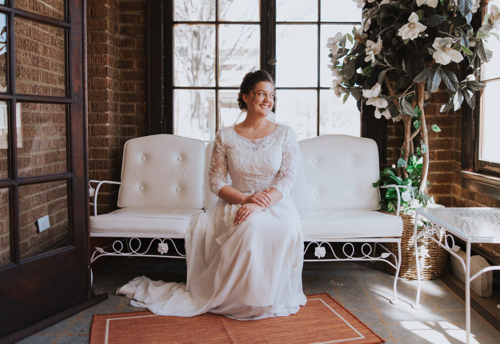 Bride sits on sofa for soft lighting on wedding day