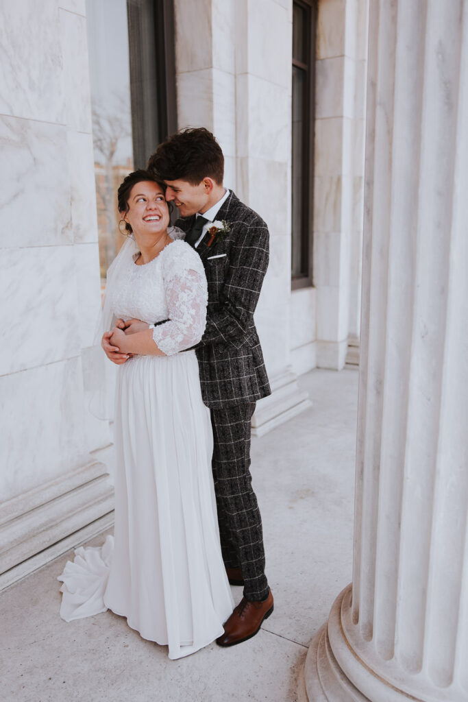 Bride and groom embrace outside of Toledo Museum of Artt
