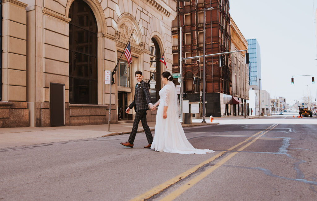 Bride and groom walk across street for wedding in Ohio